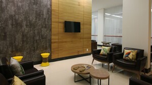 Un área de estar moderna con sofás de cuero, paneles de madera y un televisor de pantalla plana en la pared.