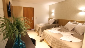Habitación de hotel con dos camas, un televisor, una puerta de madera y una planta.
