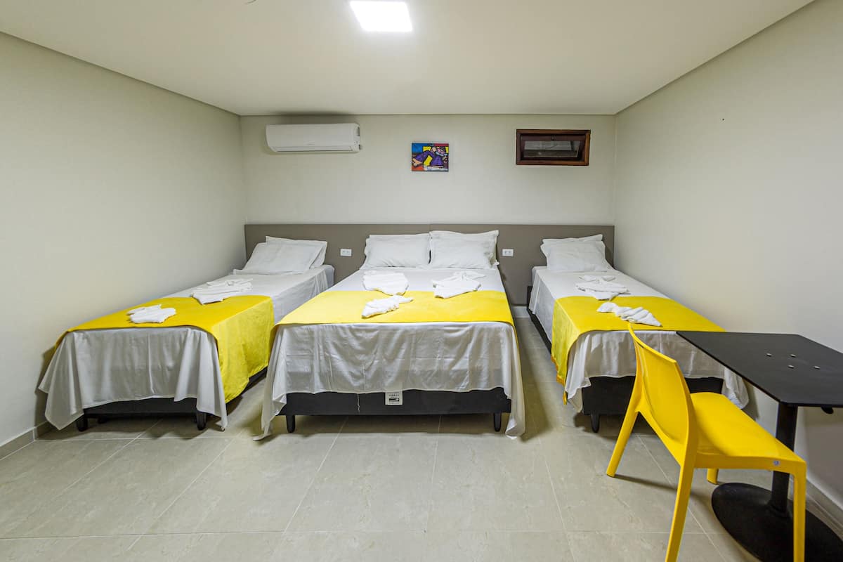 A room with three beds, a table, and a chair.