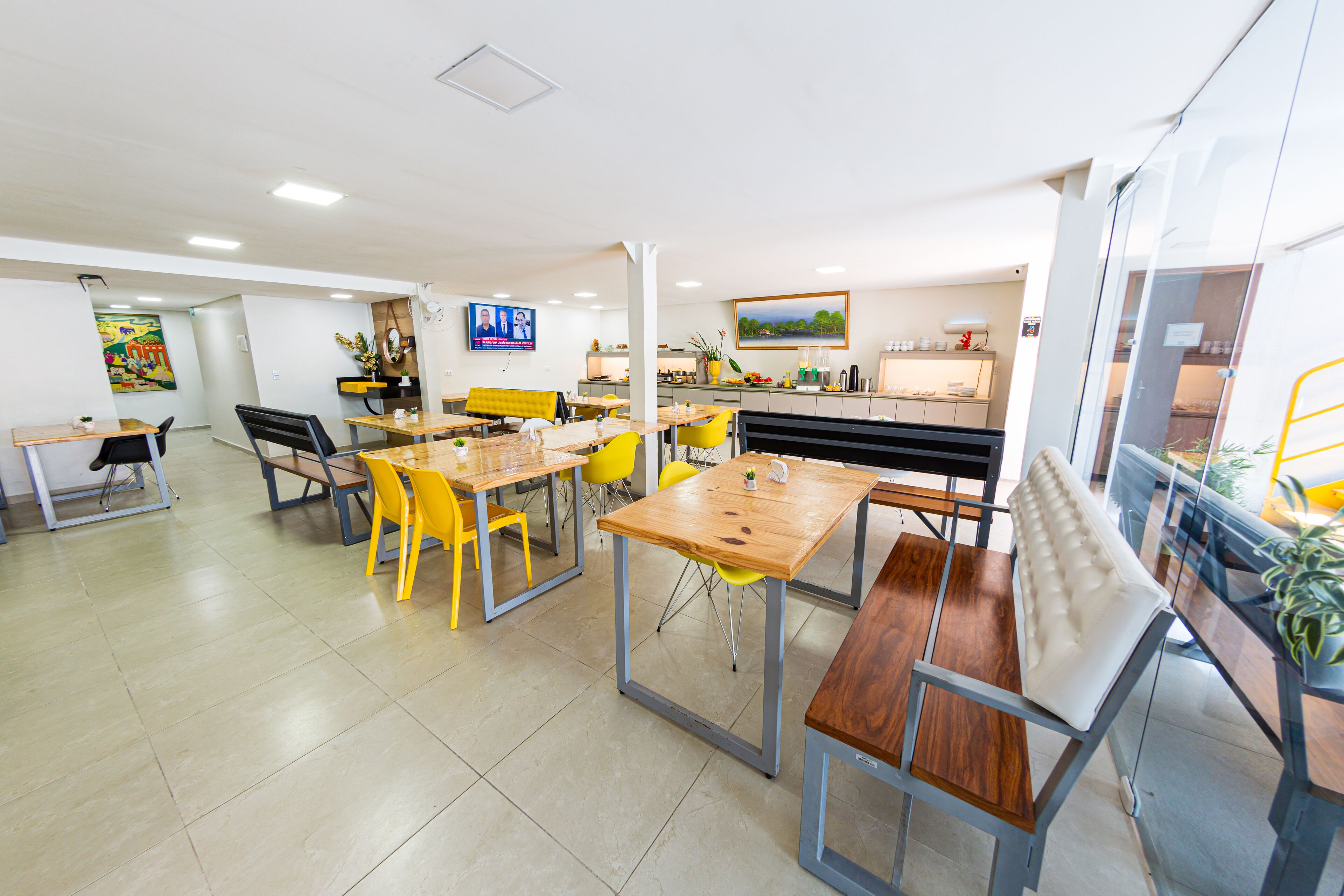 A modern dining area with yellow chairs, wooden tables, and a bench.