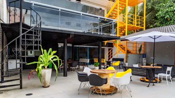 An outdoor seating area with tables and chairs, a staircase, and a potted plant. - Pousada Maanaim (Ipojuca)