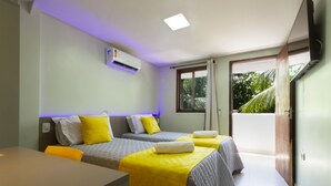 A hotel room with two beds, a table, and an air conditioning unit. - Pousada Maanaim (Ipojuca)