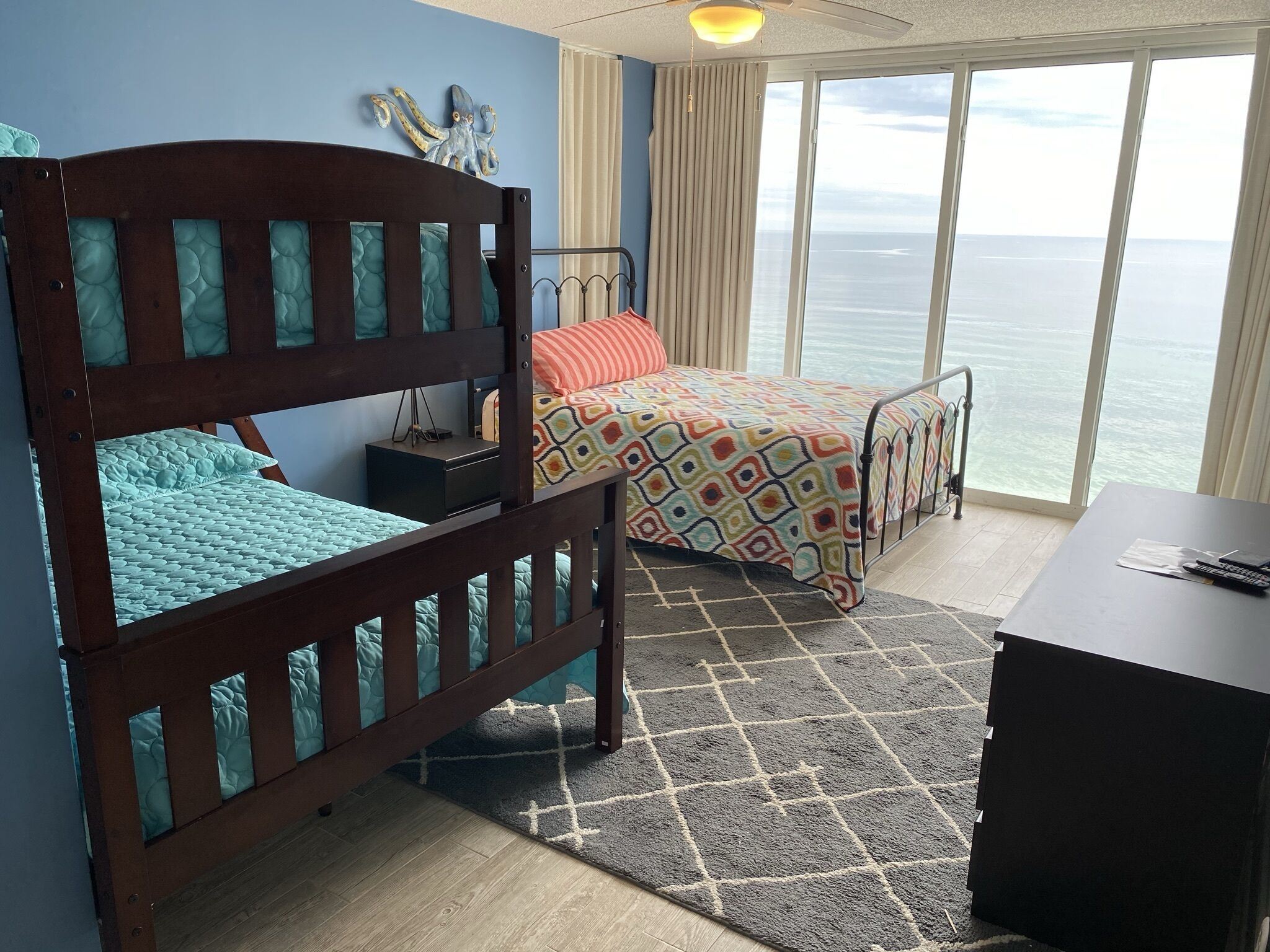 A room with two beds, a desk, and a view of the ocean.