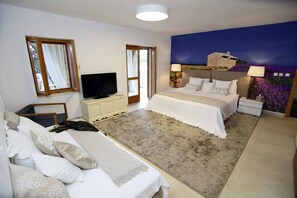 A bedroom with a bed, a TV, a desk, and a painting of a landscape.