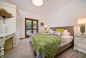 A bedroom with a bed, bedside tables, a dresser, and a window with a view of trees. - Luxury Villa Sounds of Nature with Pool (Selca)