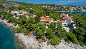 Vue aérienne d’un village côtier avec ses maisons, un littoral rocheux et des eaux d’un bleu limpide.