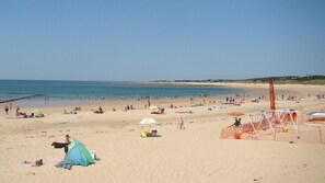 A beach with people, tents, and beach equipment.