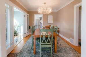 Enjoy meals in this stylish dining area with a long table and six comfortable chairs, a beautiful chandelier, and a framed inspirational quote on the wall.