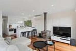 Relax in a spacious living area with a large flat-screen TV, comfortable seating, and a well-equipped kitchen.