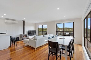 Relax in a spacious living area with a dining table, sofa, and TV, offering a view of the outdoors.