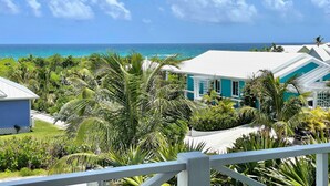 A coastal property with a view of the ocean, surrounded by lush greenery and a white fence.