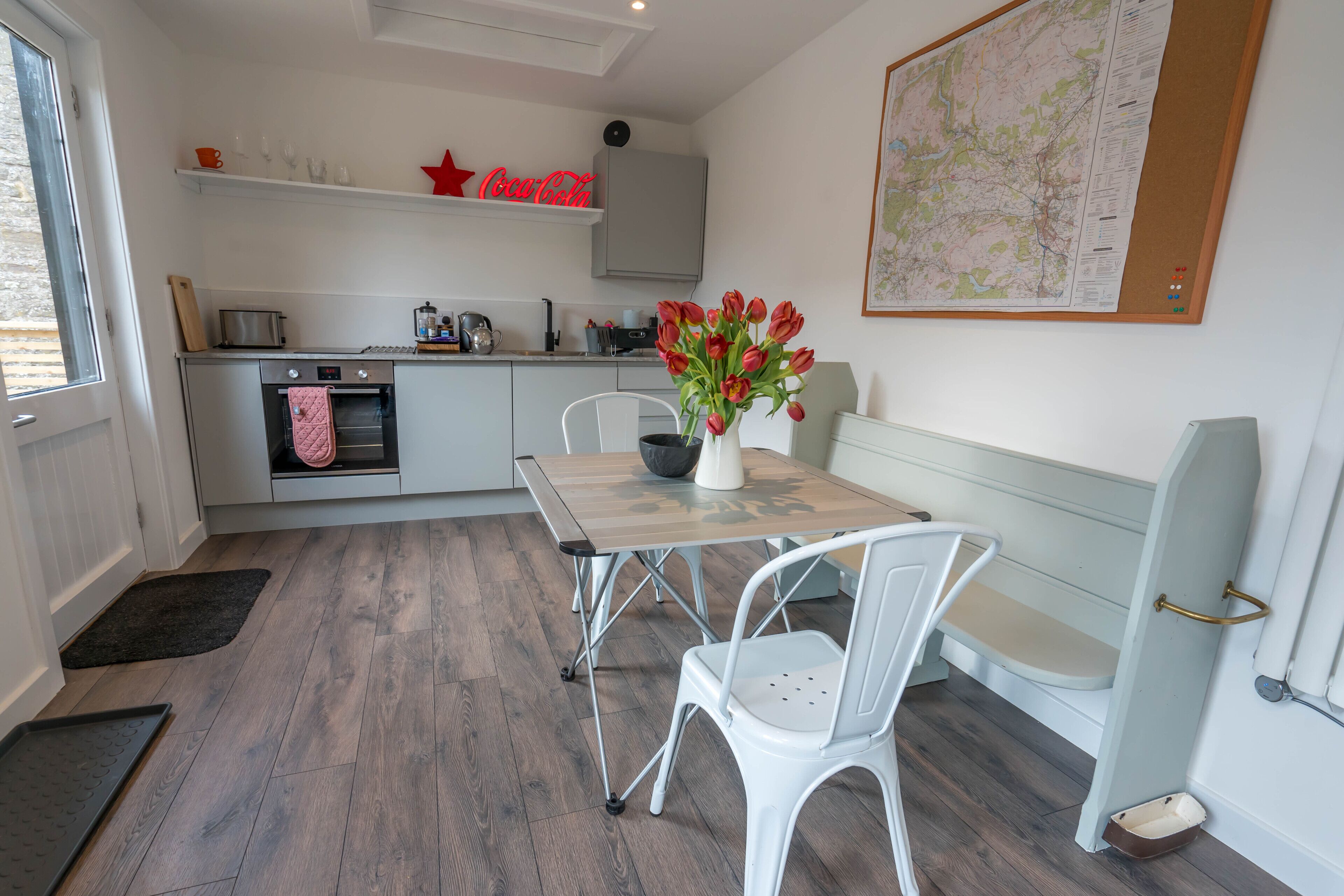 A modern kitchen with a dining area, including a table, chairs, and a map on the wall.
