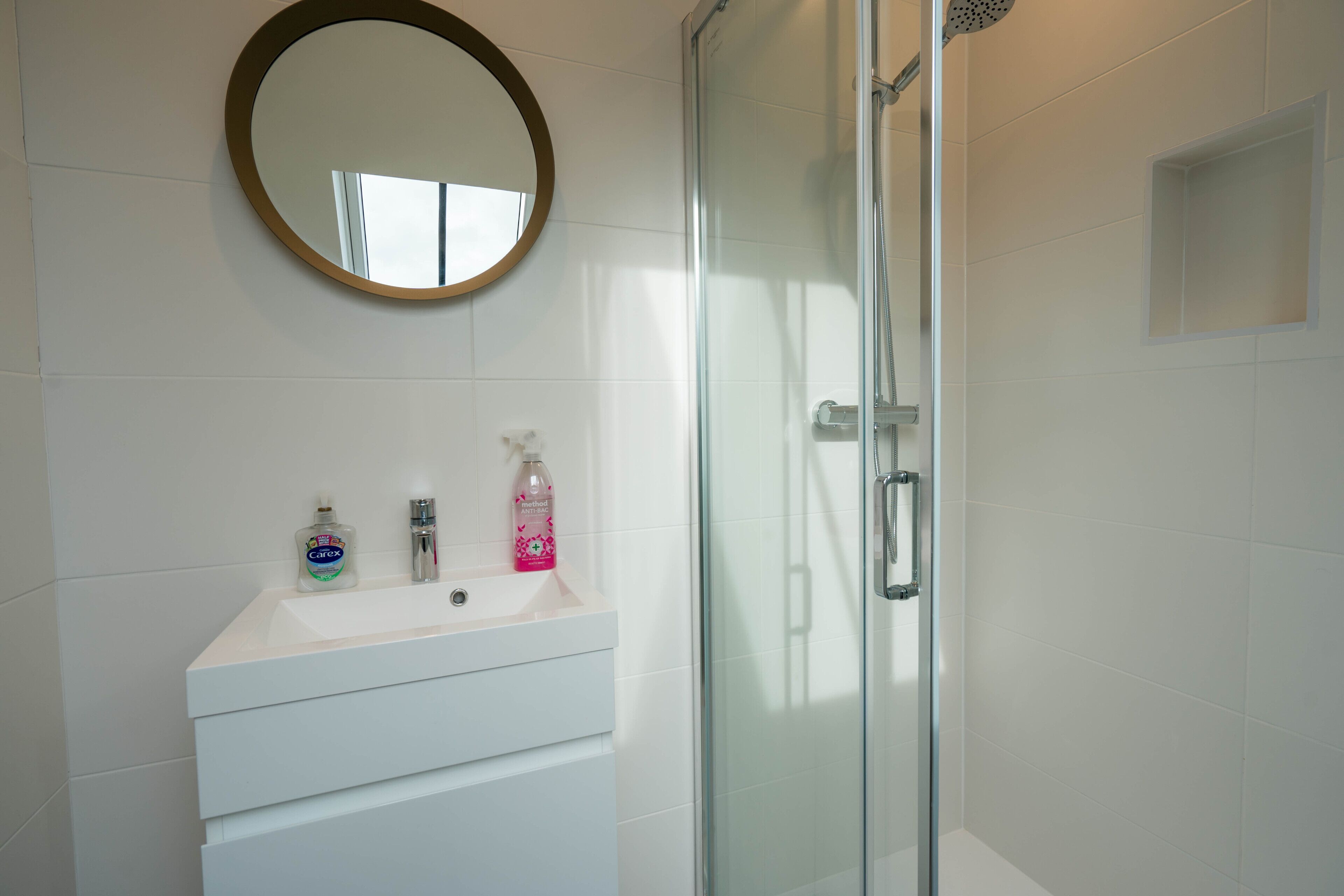 Un bagno con un lavandino bianco, uno specchio e un box doccia in vetro.