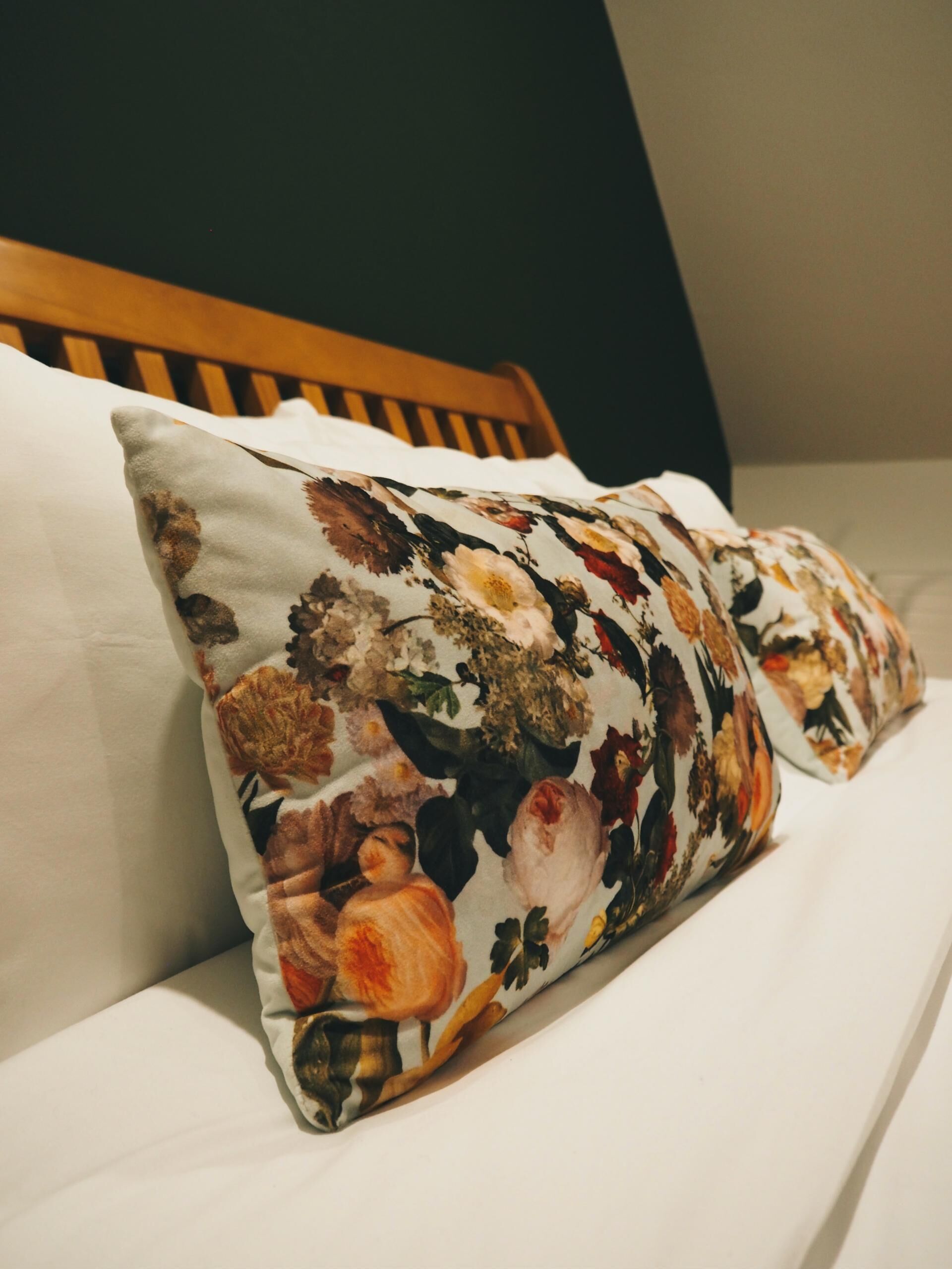 A bed with a floral pillow and a wooden headboard.
