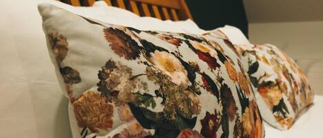 A bed with a floral pillow and a wooden headboard.