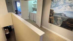 Una escalera conduce a un lavadero con un cuadro de paisaje grande en la pared.