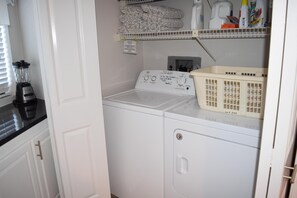 Un espace buanderie comprenant un lave-linge, un sèche-linge et un panier posé sur le plan de travail.