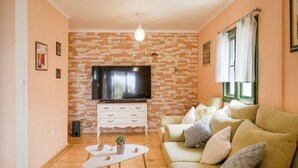 Ein Wohnzimmer mit Backsteinwand, Flachbildfernseher, weißem Sofa und Couchtisch.