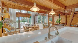 Une cuisine spacieuse dotée d’un grand îlot central, de poutres en bois et de luminaires suspendus.