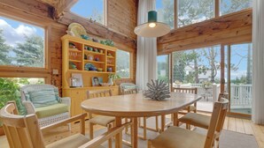 Un intérieur en bois comprenant une table à manger, des chaises et une étagère où sont rangés de la vaisselle.