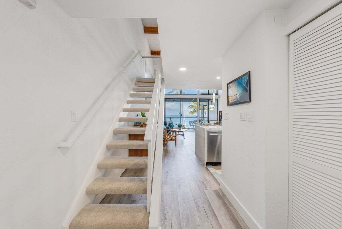 A modern interior with a staircase leading to a dining area and kitchen.