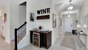 Ein zeitgemäßes Interieur mit einer Treppe, einem Weinkühlschrank und einem Flur, der zu einer Tür führt.