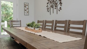 Een eetruimte met een houten tafel, vier stoelen, een wit tapijt en decoratieve wandkunst.
