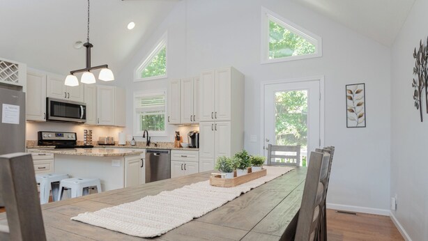 Een moderne keuken met witte kasten, een houten eettafel en uitzicht op de omgeving.