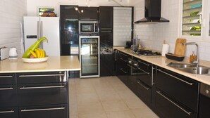 Una cucina moderna con mobili neri, un piano di lavoro bianco, un forno integrato e un microonde.