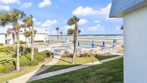 Um resort com área de piscina, palmeiras e vista para o oceano.