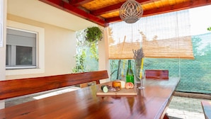 A wooden dining table with a bench, a bottle of wine, and a glass on it. - Holiday Home Vesna with pool and children area (Suhovare)
