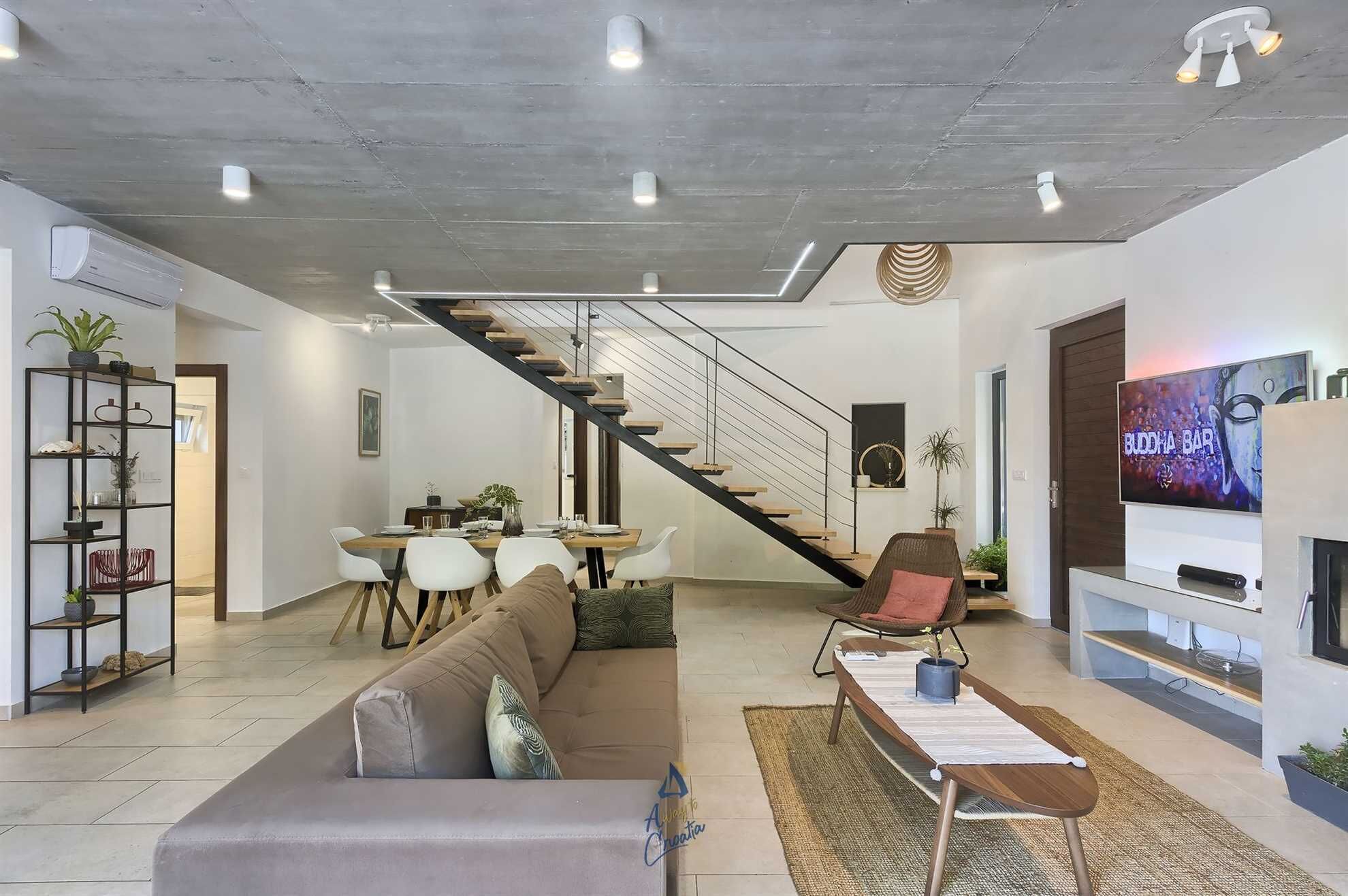 Uma sala de estar moderna com escada, área de jantar e televisão.