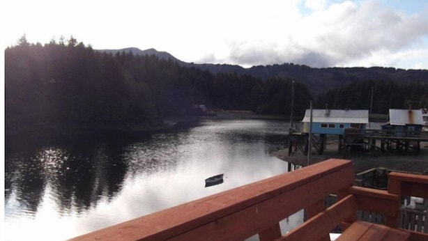 Un molo di legno che si protende in un lago tranquillo, con una collina boscosa sullo sfondo.