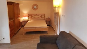 A bedroom with a bed, bedside table, lamp, wardrobe, and a sofa. - Rent a villa overlooking the Gulf of Valinco (Sartène)