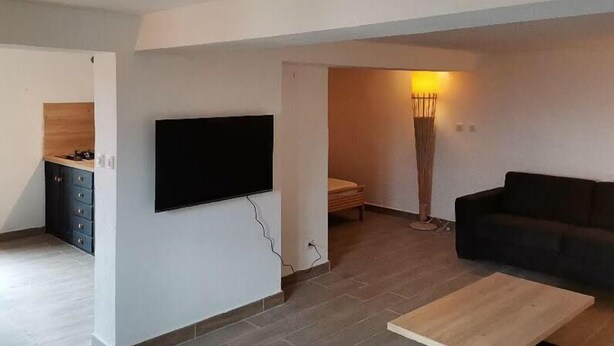 A living room with a flat-screen TV mounted on the wall, a dark sofa, and a coffee table. - Rent a villa overlooking the Gulf of Valinco (Sartène)