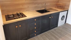 A compact kitchen with a gas stove, a sink, and a built-in washing machine. - Rent a villa overlooking the Gulf of Valinco (Sartène)