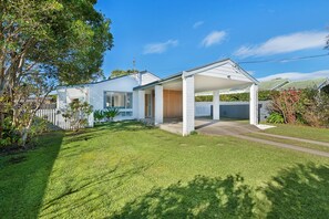 A modern two-story house with a covered porch, a fenced backyard, and a well-maintained lawn.