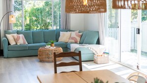 Ein Wohnzimmer mit einem türkisblauen Sofa, einem Holztisch und einem Esstisch.