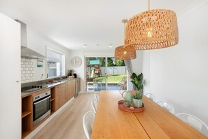 A modern kitchen with wooden cabinets, a built-in oven, and a dining area with a wooden table and chairs.