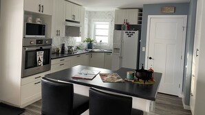 A modern kitchen with white cabinets, stainless steel appliances, and a central island with chairs. -  Loft 902 with Sunsets from the 14x32 covered deck almost every morning! (Estevan)