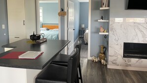 A modern kitchen with a dining area, a bed in the adjacent room, and a fireplace. -  Loft 902 with Sunsets from the 14x32 covered deck almost every morning! (Estevan)
