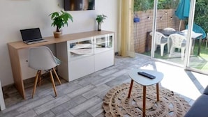 A modern room with a desk, chair, and a small table with a remote control. - Studio 100m from the beach, patio, car park, air conditioning (Six-Fours-les-Plages)