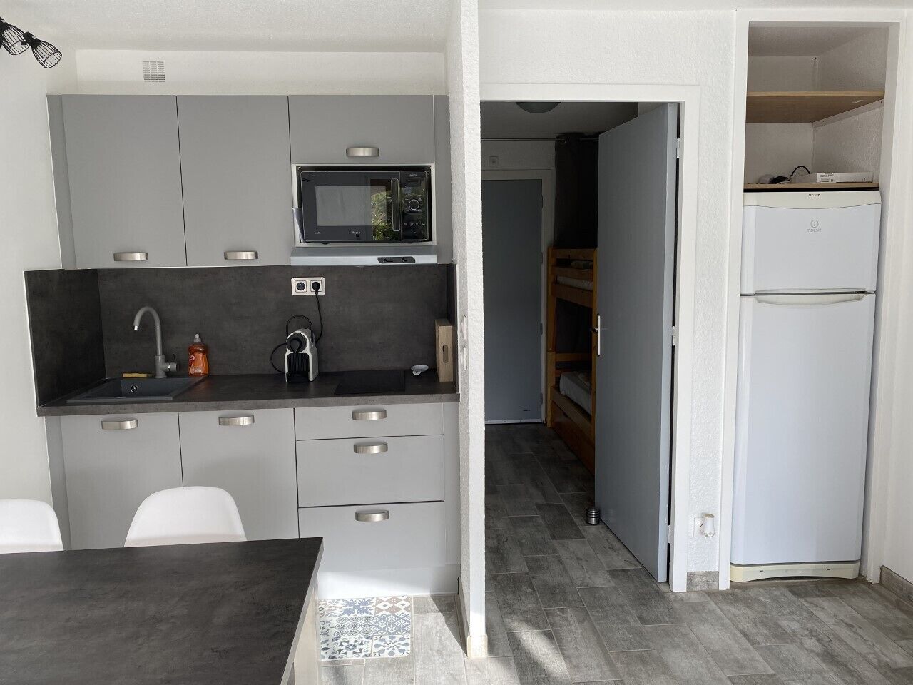 A compact kitchen with a microwave, sink, and a small refrigerator.