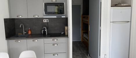 A compact kitchen with a microwave, sink, and a small refrigerator.