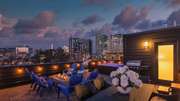 Una terrazza sul tetto con posti a sedere all'aperto, un barbecue e vista sulla città al crepuscolo.