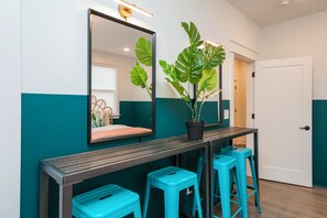 Une salle de bain moderne avec un grand miroir, une plante en pot et trois tabourets bleus.