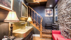 Un bagno d'epoca con una scala in legno, una panca rossa e un lavandino vintage.