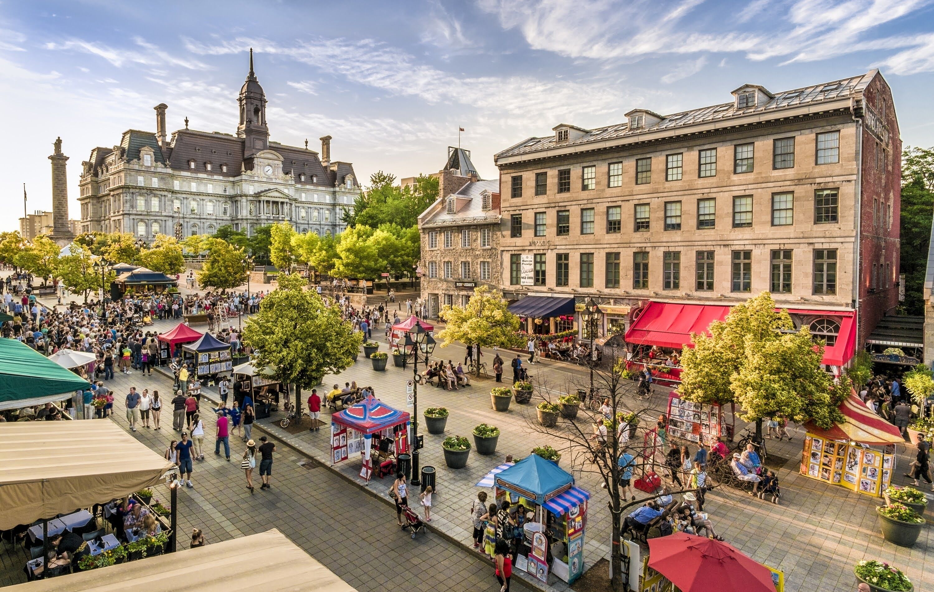 Ein belebter Platz mit historischen Gebäuden, Straßencafés und Marktständen.