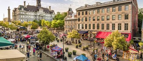 Ein belebter Platz mit historischen Gebäuden, Straßencafés und Marktständen.