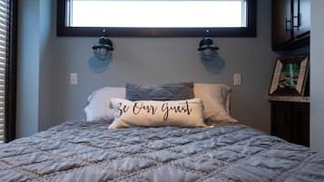 Un dormitorio con cama, dos lámparas de pared, una ventana y una almohada con texto.
